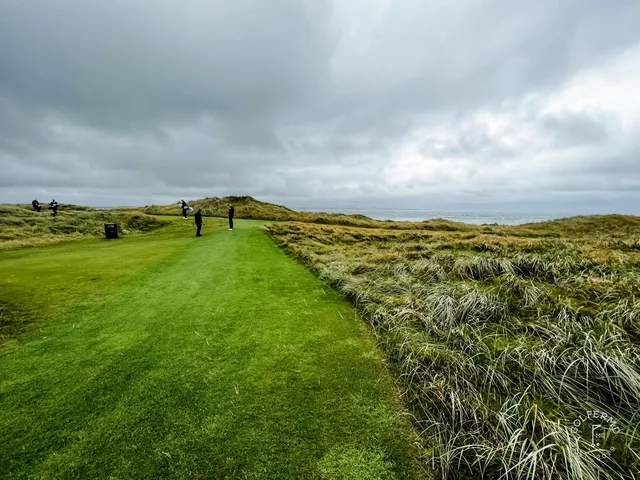 A wide panorama at Doonbeg, with several holes in the dunes and the water beyond.