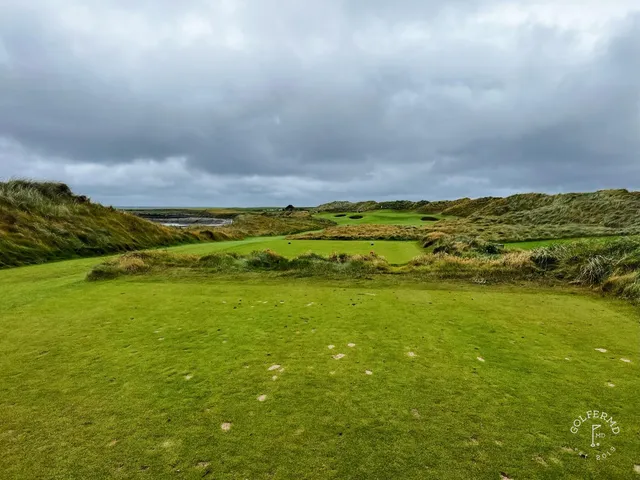 A green and flagstick at Doonbeg seen from the fairway, with the sea on the horizon.