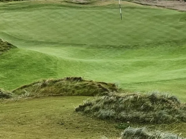 A tee shot at Doonbeg, the fairway dropping toward a green above the beach.