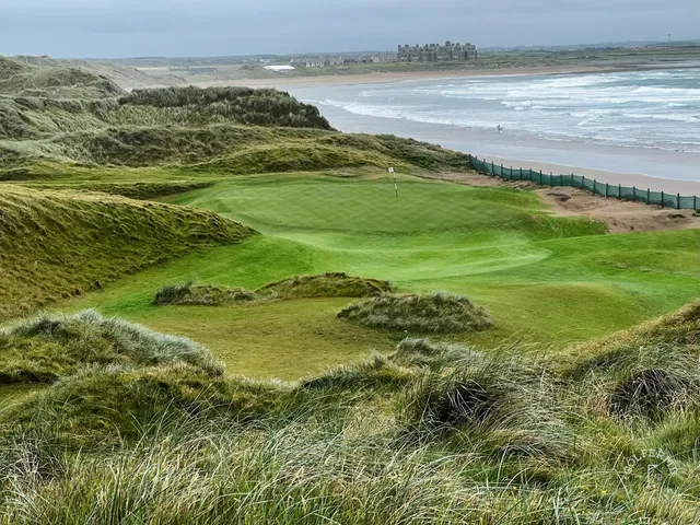 A close view of a green at Doonbeg, the flagstick framed by marram grass.
