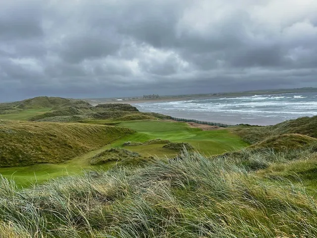 A green and flagstick at Doonbeg, a deep bunker short of the hole and the dunes behind.