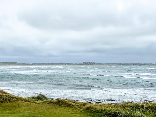 A close flagstick at Doonbeg, with the water just beyond the green.