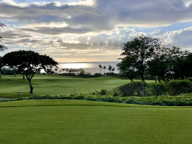 A golfer hitting a shot at the Emerald Course, with the fairway and ocean ahead.