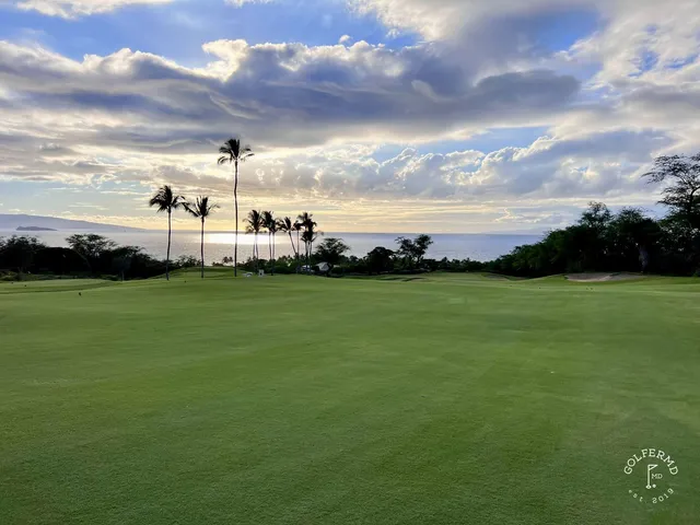 Golfers on a tee at the Emerald Course, with the coast behind them.