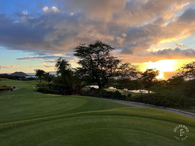 A wide fairway at the Emerald Course, with the ocean and mountains in the distance.