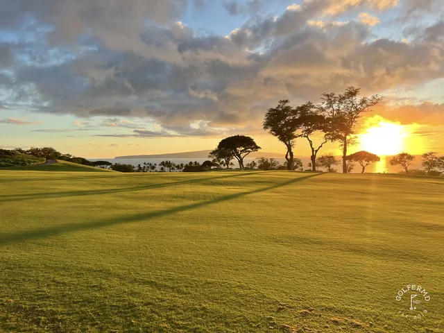 A group posing for a photo at the Emerald Course, with the ocean behind them.
