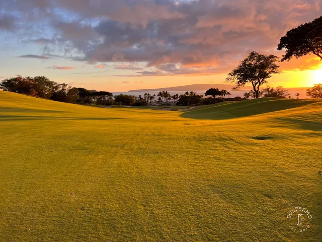 A close view of a green and flagstick at the Emerald Course, with the Pacific behind the hole.