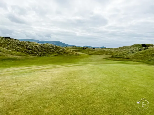A green at Waterville above the beach, with the flagstick and the bay beyond.