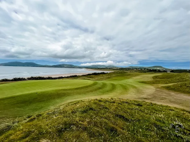 A fairway at Waterville bending toward the ocean, with the mountains on the horizon.