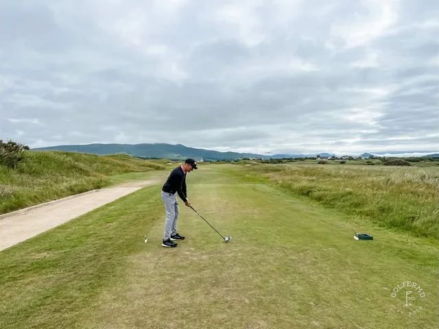 A golfer putting at Waterville, with the dunes and the bay behind the green.