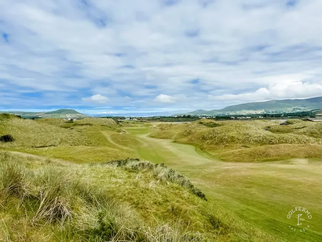 A green at Waterville guarded by sand, with the mountains behind the hole.