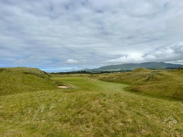 Golfers walking a fairway at Waterville, with the ocean and the mountains beside them.