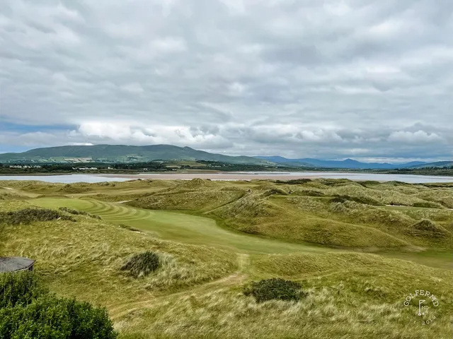A green at Waterville with the flagstick, sand around the hole, and the mountains beyond.