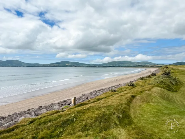 A golfer hitting an approach at Waterville, with the bay behind the green.