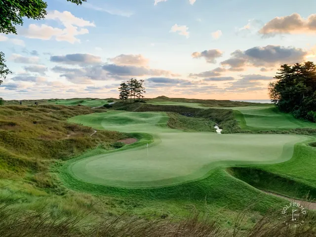 A green and flagstick on the Straits Course, with a bunker in front and the lake behind the hole.