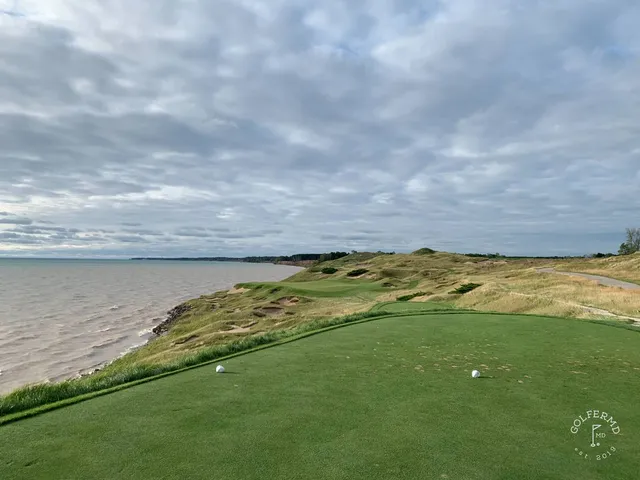 A golfer hitting a shot on the Straits Course, with Lake Michigan ahead.
