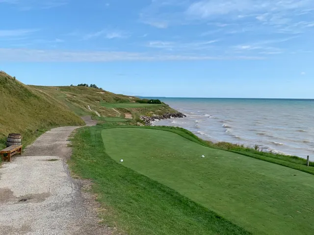 Golfers on a tee on the Straits Course, with the lake behind them.
