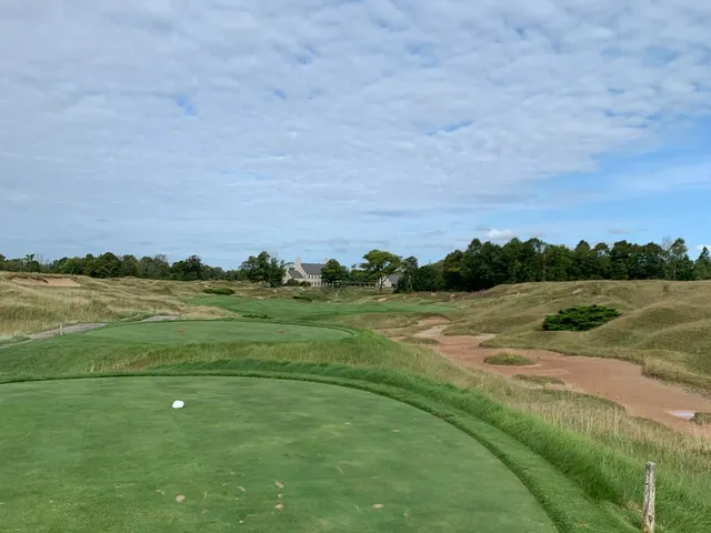 A fairway on the Straits Course bending through the dunes toward a distant green.