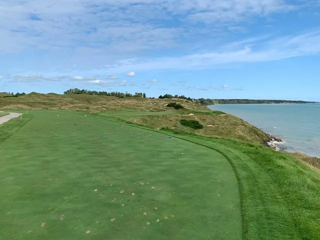A golfer putting on the Straits Course, with the dunes behind the green.