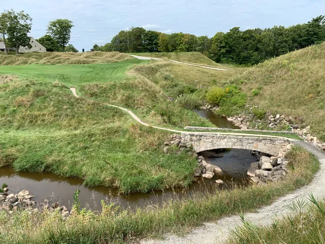 A tee shot on the Straits Course, the fairway dropping toward a green above the water.