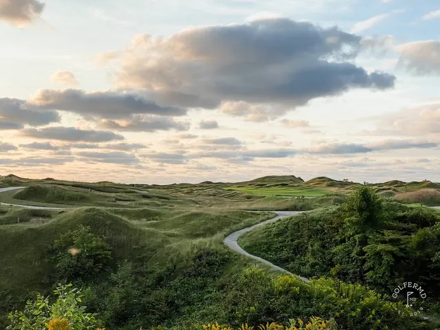 Golfers walking a fairway on the Straits Course, with the lake beside the hole.