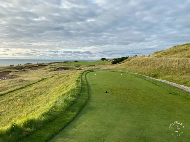 A green on the Straits Course with the flagstick, sand around the hole, and the water beyond.