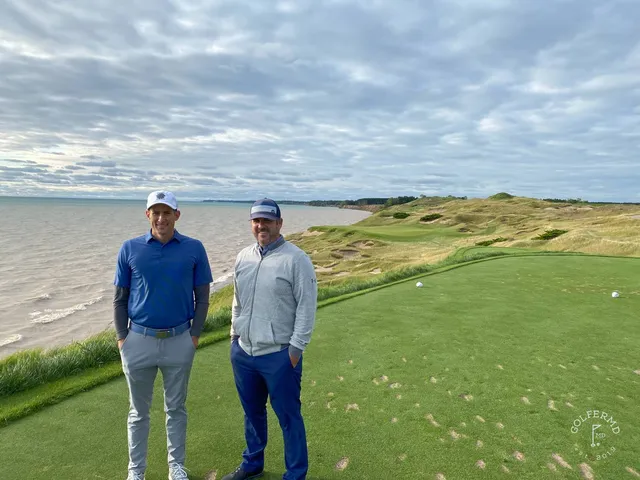 Golfers on a green on the Straits Course, with the dunes and the water behind them.