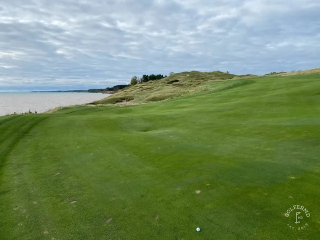 A short hole on the Straits Course, the flagstick standing in the dunes above the lake.