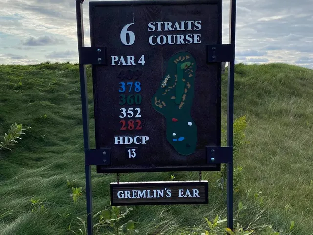 A pot bunker in the foreground on the Straits Course, with the green and the water beyond.