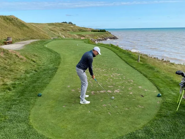 Two bunkers flanking a green on the Straits Course, with the flagstick and the lake.