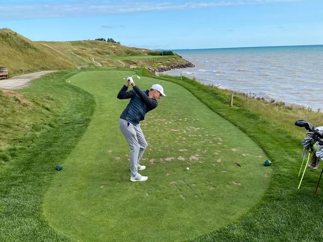 A narrow fairway on the Straits Course pinched by dunes, running toward the water.