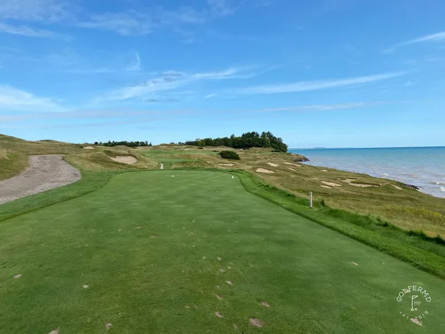 A flagstick on the Straits Course against the sky, the green falling toward the lake.