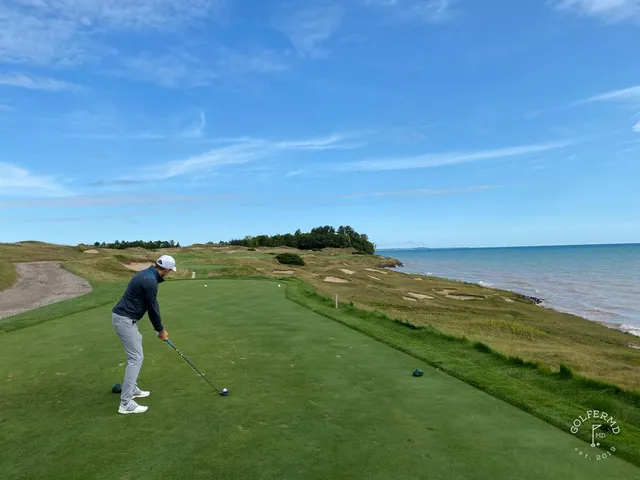 Golfers waiting on a tee on the Straits Course, the fairway and the lake in front of them.