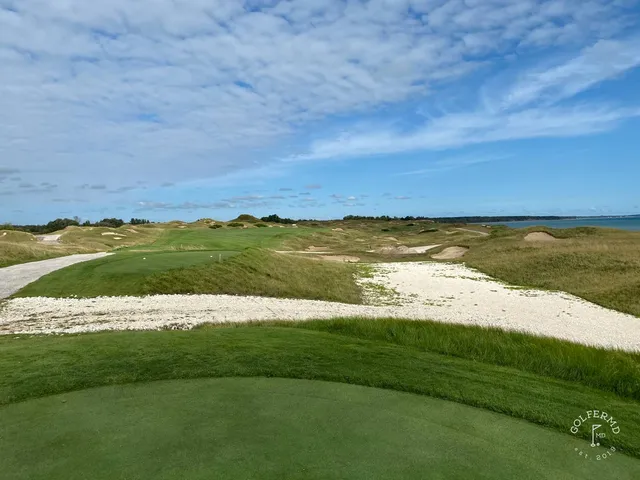 The shore and the water from the edge of a green on the Straits Course.