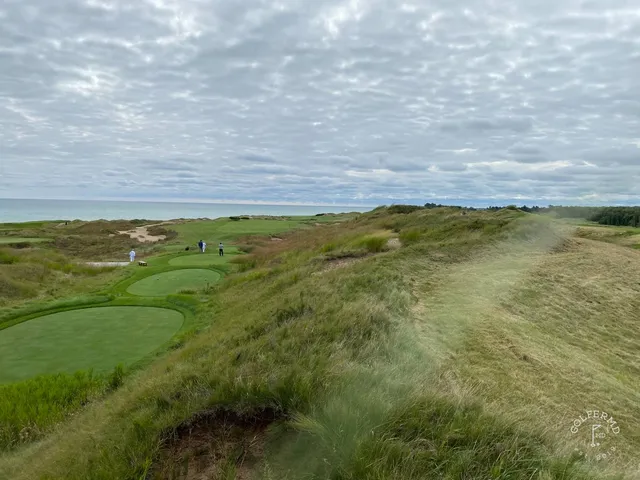 A golfer walking off a green on the Straits Course, the next tee set in the fescue.