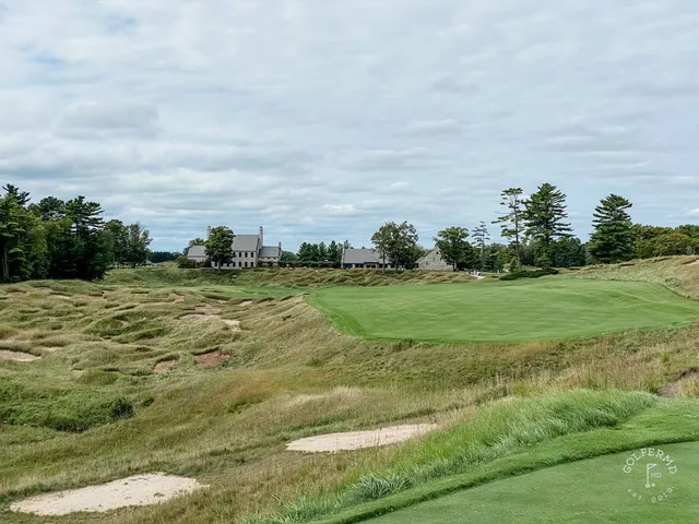 The dunes closing around a green on the Straits Course, with Lake Michigan behind the pin.