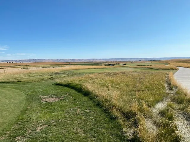 A tee view at Wine Valley, the fairway running left to right past a bunker toward a distant green.