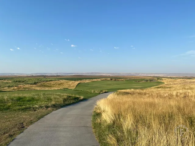 An elevated green at Wine Valley, with the flagstick, a front-left bunker, and the valley beyond.