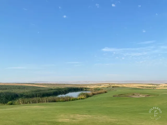 A close view of a flagstick at Wine Valley, with a bunker short of the green and the fairway behind.