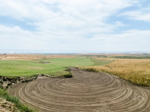 A broad view across several holes at Wine Valley, with greens, bunkers, and the hills under a blue sky.