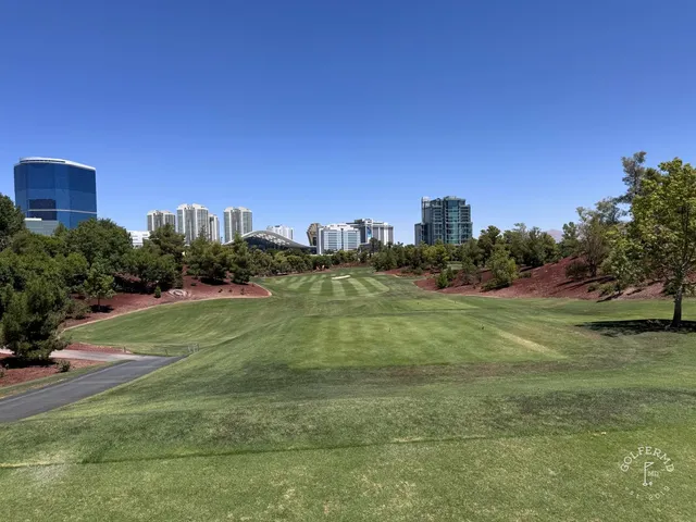 A golfer hitting a shot at Wynn Golf Club, with the fairway and the Strip ahead.