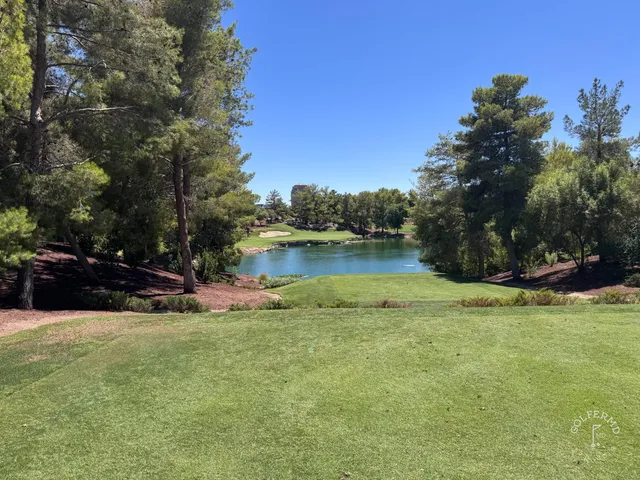 A green and flagstick at Wynn Golf Club, with a sand bunker in front and the Strip beyond.