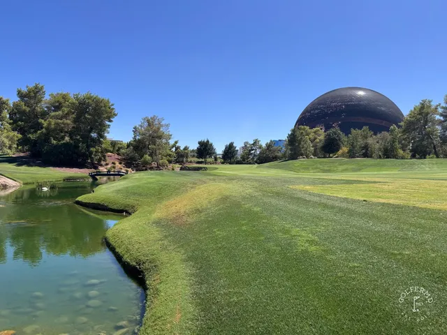 A fairway at Wynn Golf Club lined with palms, with the mountains on the horizon.